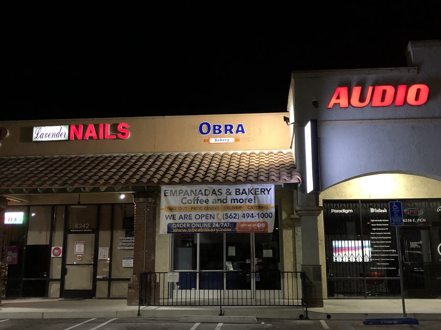 The shop front at night with the Obra sign lit